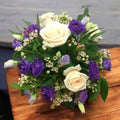 Guest table arrangement with cream roses and lisianthus