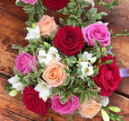 Table arrangement colored roses and white freesias