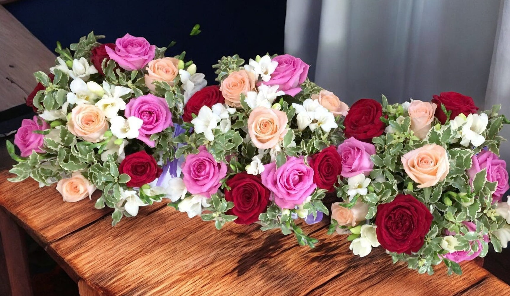 Table arrangement colored roses and white freesias