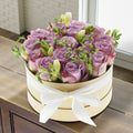 Purple roses and freesias in a round box