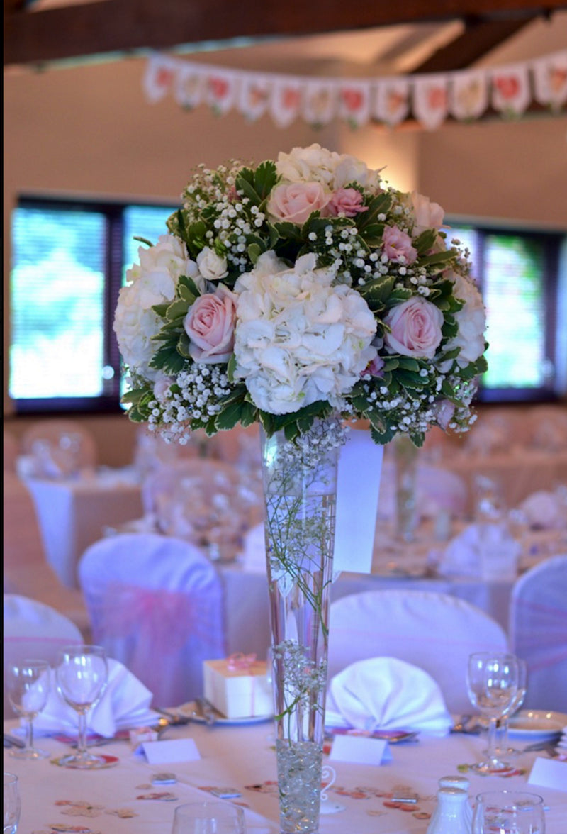 Un super aranjament de masa realizat din trandafiri roz, hortensii albe si floare miresei, finisat cu verdeata.