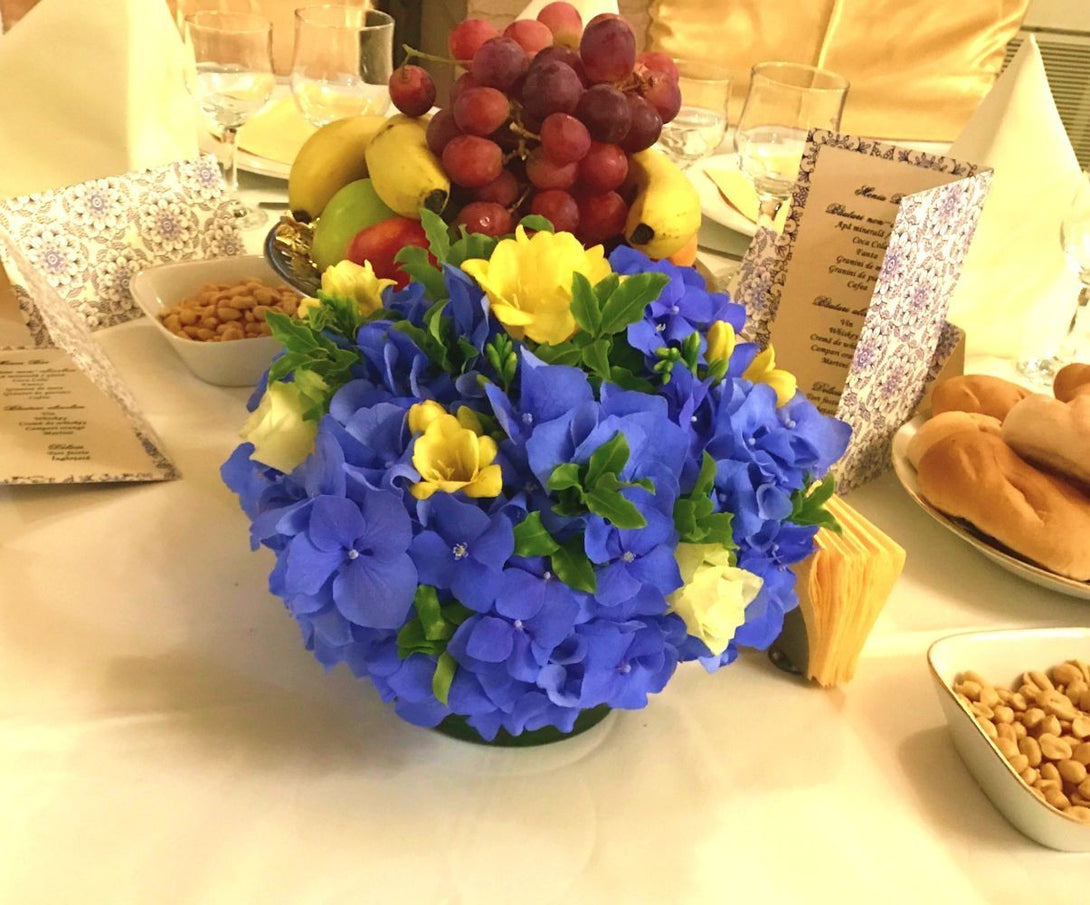 Aranjament masa nunta cu hortensii albastre si frezii galbene