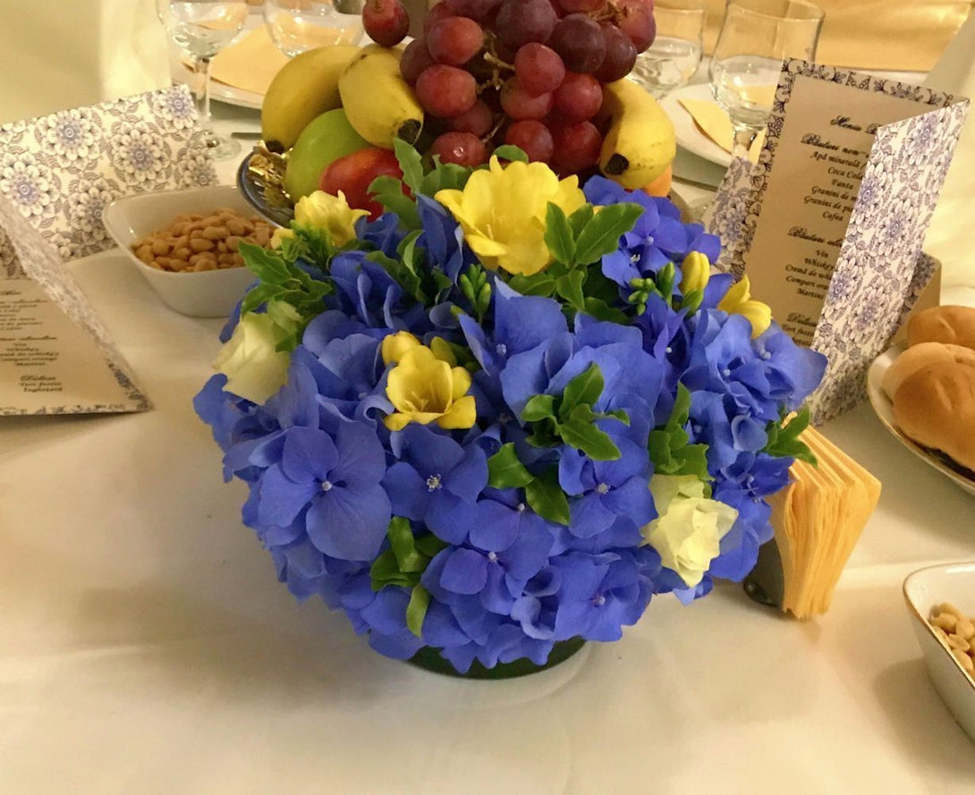 Aranjament masa nunta cu hortensii albastre si frezii galbene